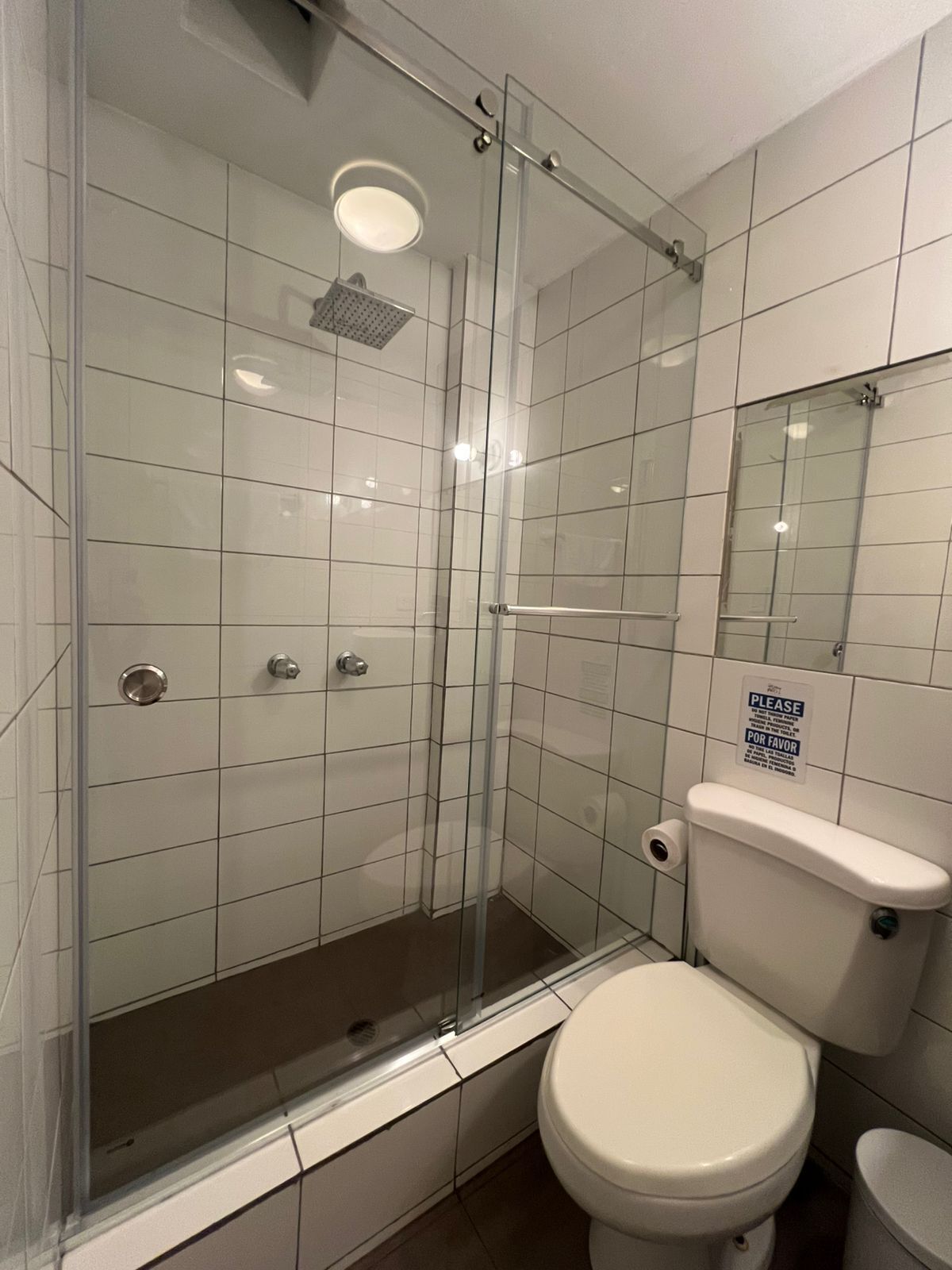 A bathroom with a glass-enclosed shower, a toilet, and a sink.