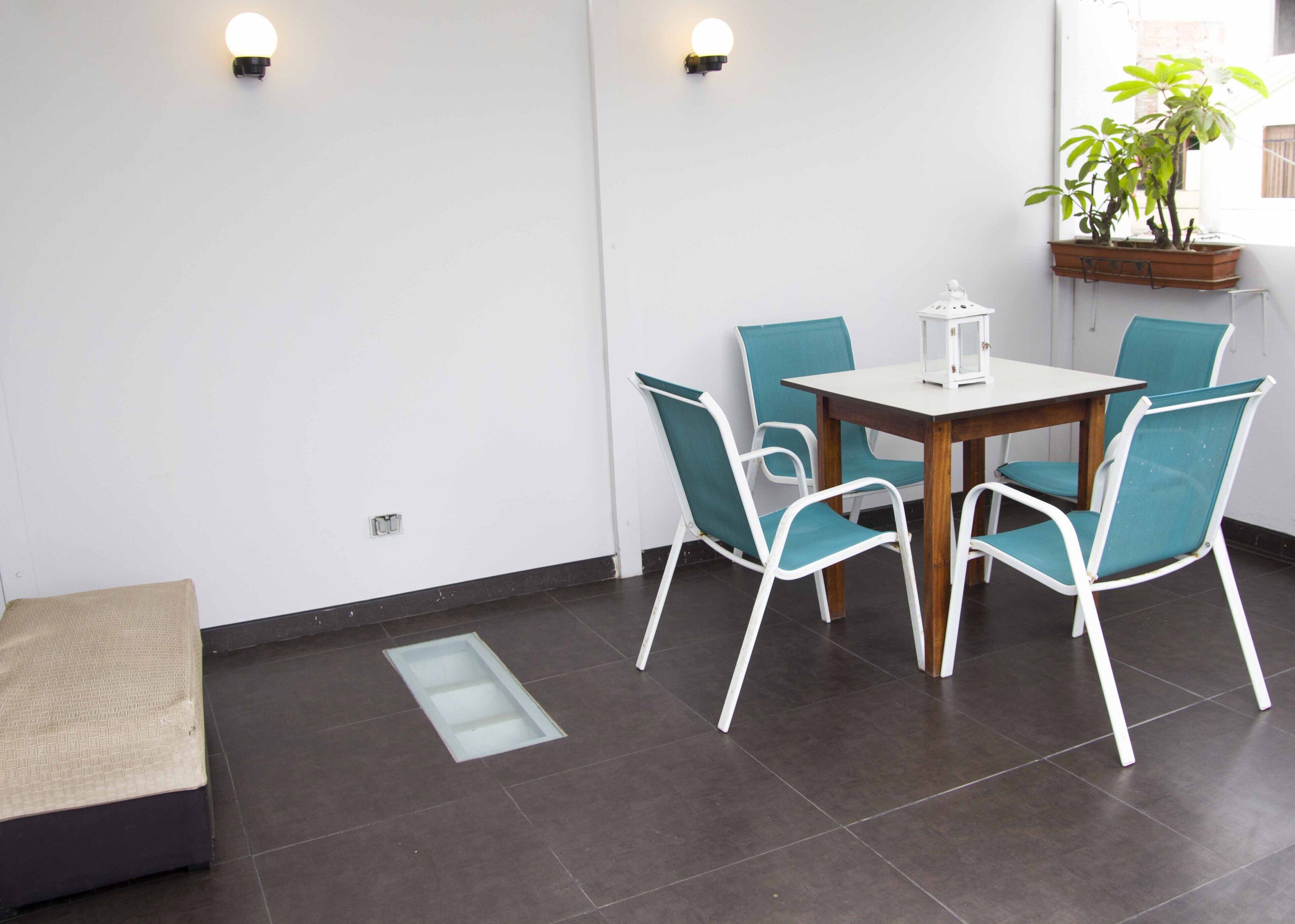 A modern room with a dining table, four chairs, a small potted plant, and a bench.