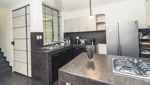 Una cocina moderna con encimeras oscuras, electrodomésticos de acero inoxidable y un florero de vidrio en la isla.