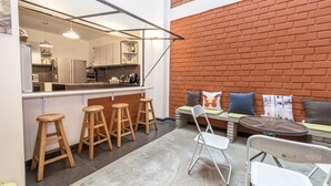 Una cocina con taburetes, mostrador y pared de ladrillo.