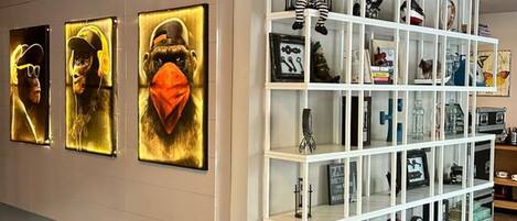 A modern interior with a white shelving unit displaying various items, a wall with framed artwork, and a marble floor.