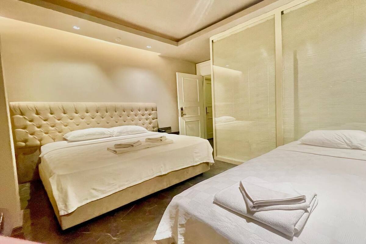 A hotel room with two beds, a large window with blinds, and a modern design.