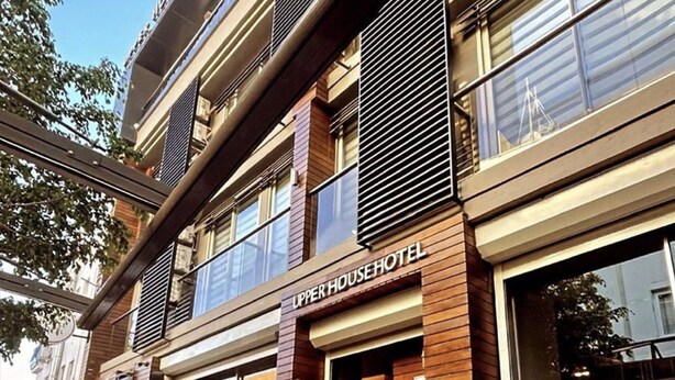 Hotel Upper House: Eksteriør med moderne facade, store vinduer og udendørs siddeområde med fletstole.