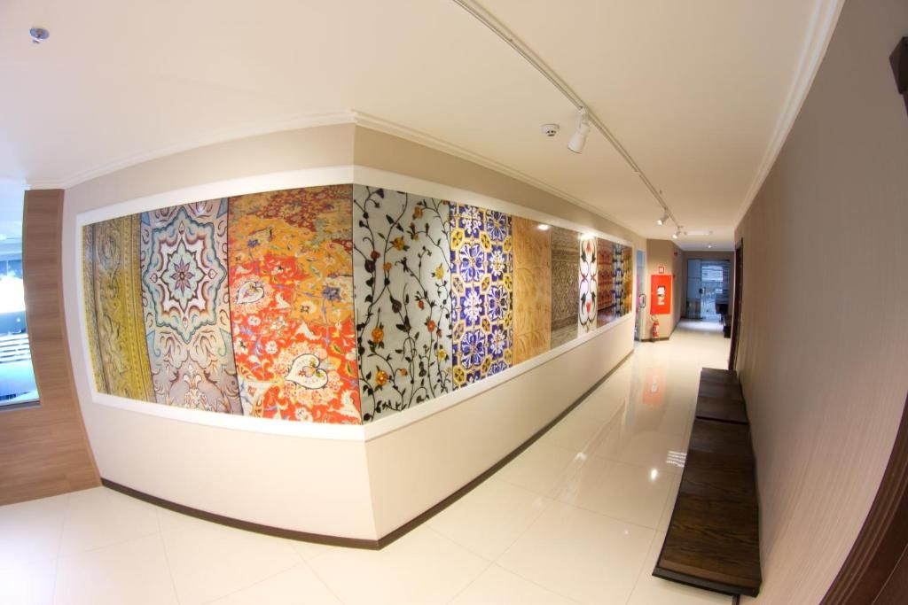 A hallway with a series of patterned tiles on the walls, a wooden bench, and a door at the end.