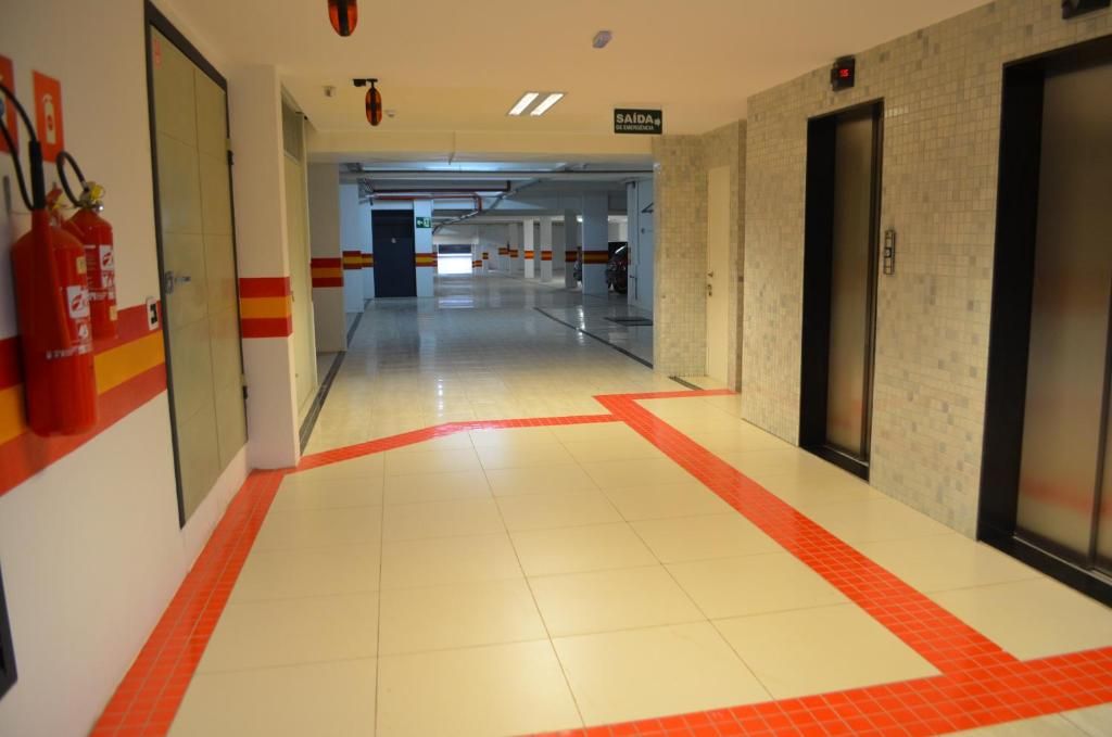 A corridor with fire extinguishers, a sign indicating an exit, and an elevator.