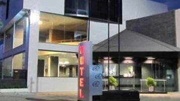 A modern hotel with a prominent neon sign reading "HOTEL" and a glass facade.