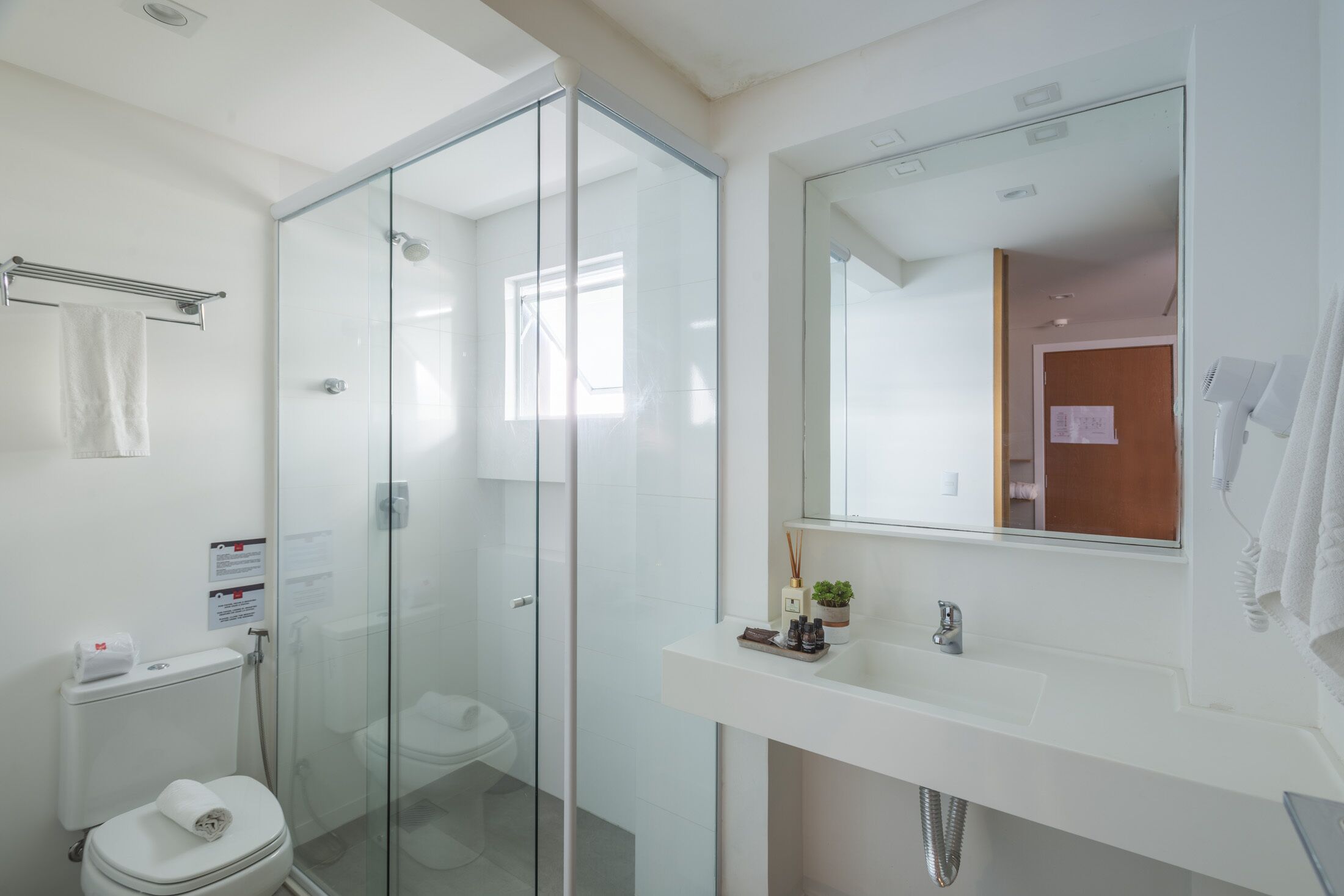 Un baño moderno con ducha envuelta en vidrio, un lavabo blanco con espejo y un inodoro.