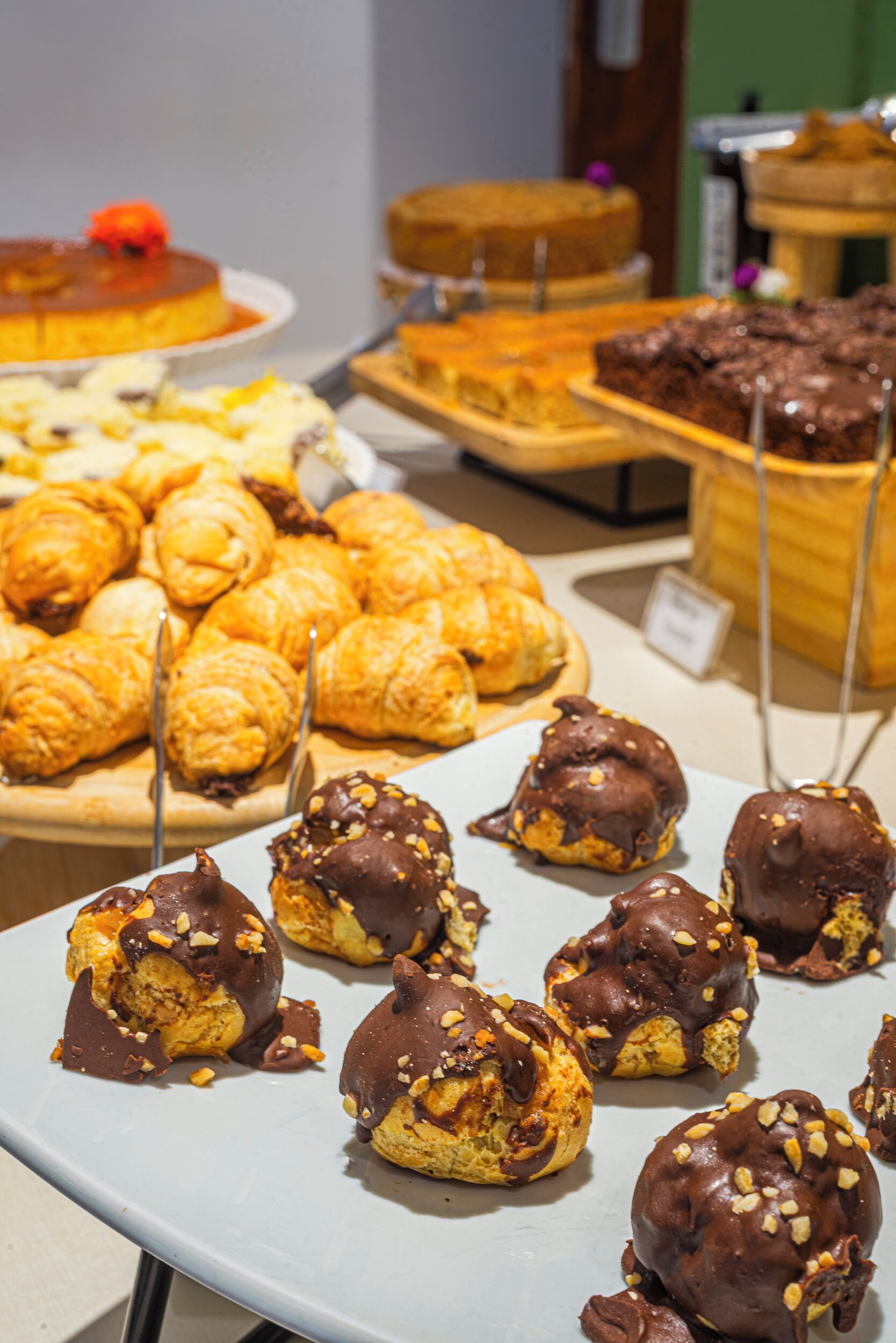 A variety of pastries displayed on trays, including croissants and chocolate-covered desserts.