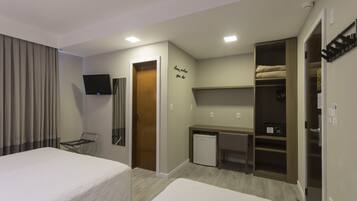 Een hotelkamer met twee bedden, een bureau, een kleine koelkast, een televisie en een kledingkast.