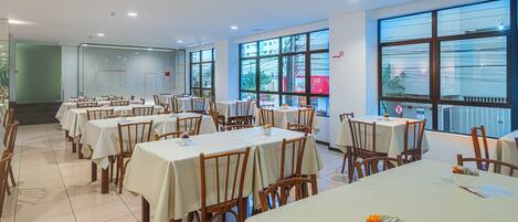 Un restaurant doté de nombreuses tables et chaises, de grandes fenêtres et d’un intérieur propre et moderne.