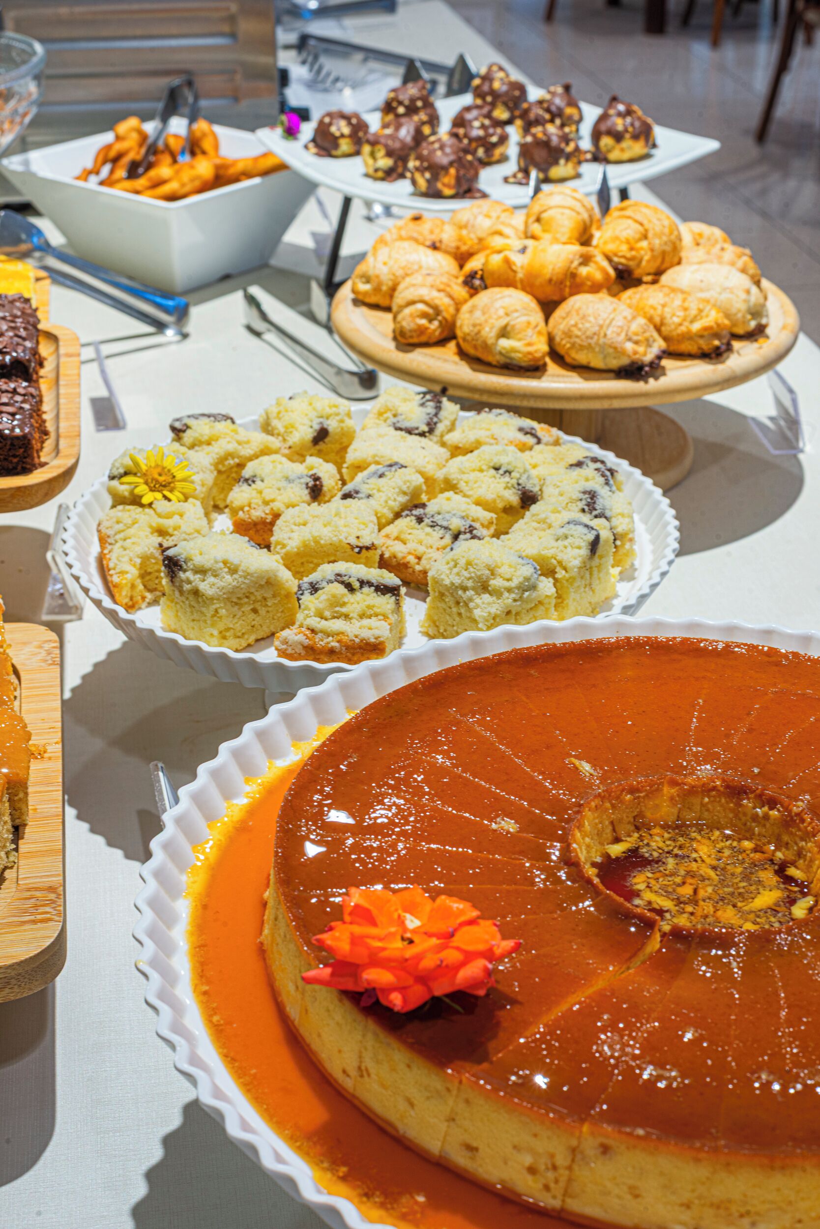 A buffet table with various desserts including a large caramel flan, mini pastries, and assorted cookies.