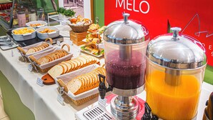 A buffet with various food items and juice dispensers. - Hotel Melo (Balneário Camboriú)