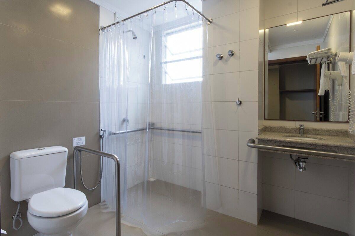 A bathroom with a toilet, shower, and sink.