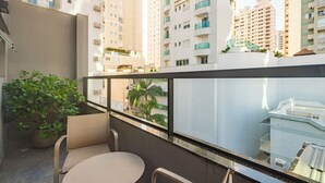 A balcony with a table and chairs, a potted plant, and a view of high-rise buildings. - Hotel Melo (Balneário Camboriú)