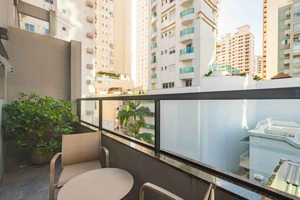 A balcony with a table and chairs, a potted plant, and a view of high-rise buildings.