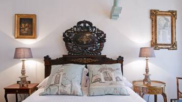 A bedroom with a wooden headboard, two bedside tables with lamps, a bed with patterned pillows, and framed artwork on the walls.