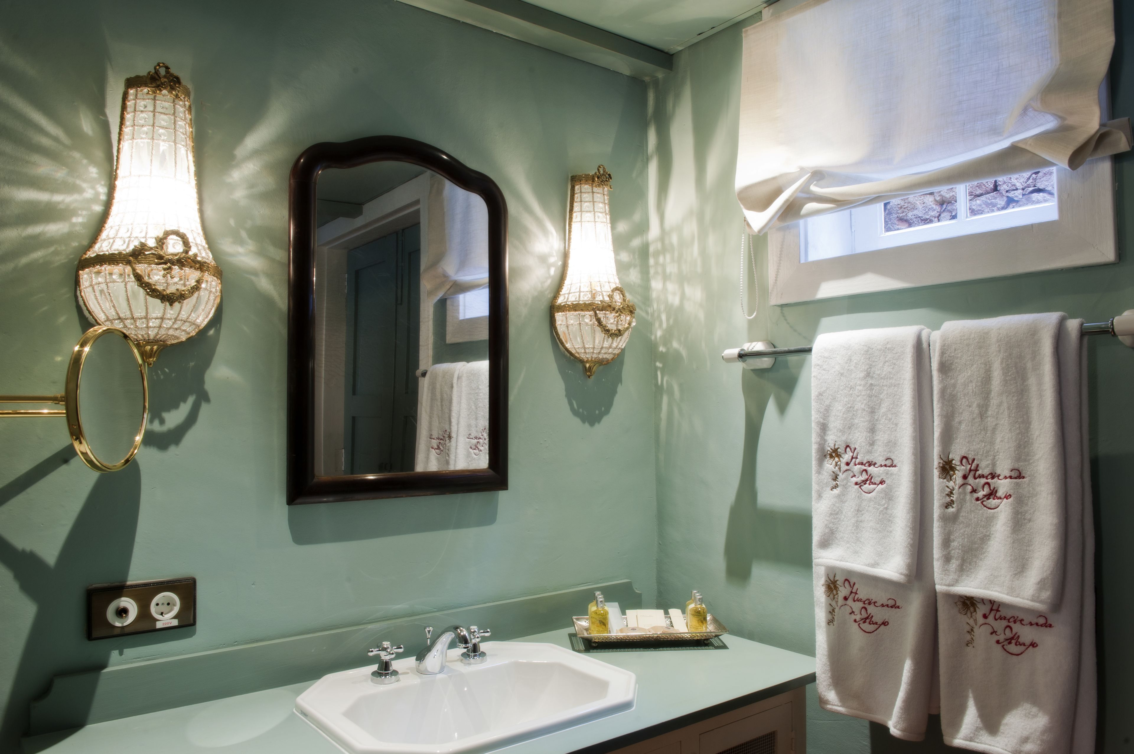 Baño con lavamanos, dos luces empotradas, un espejo y dos toallas colgadas en un perchero.
