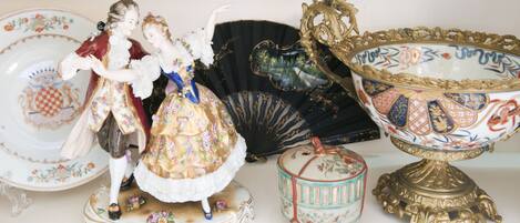 Una colección de figuritas de porcelana antiguas, un abanico y un cuenco decorativo.