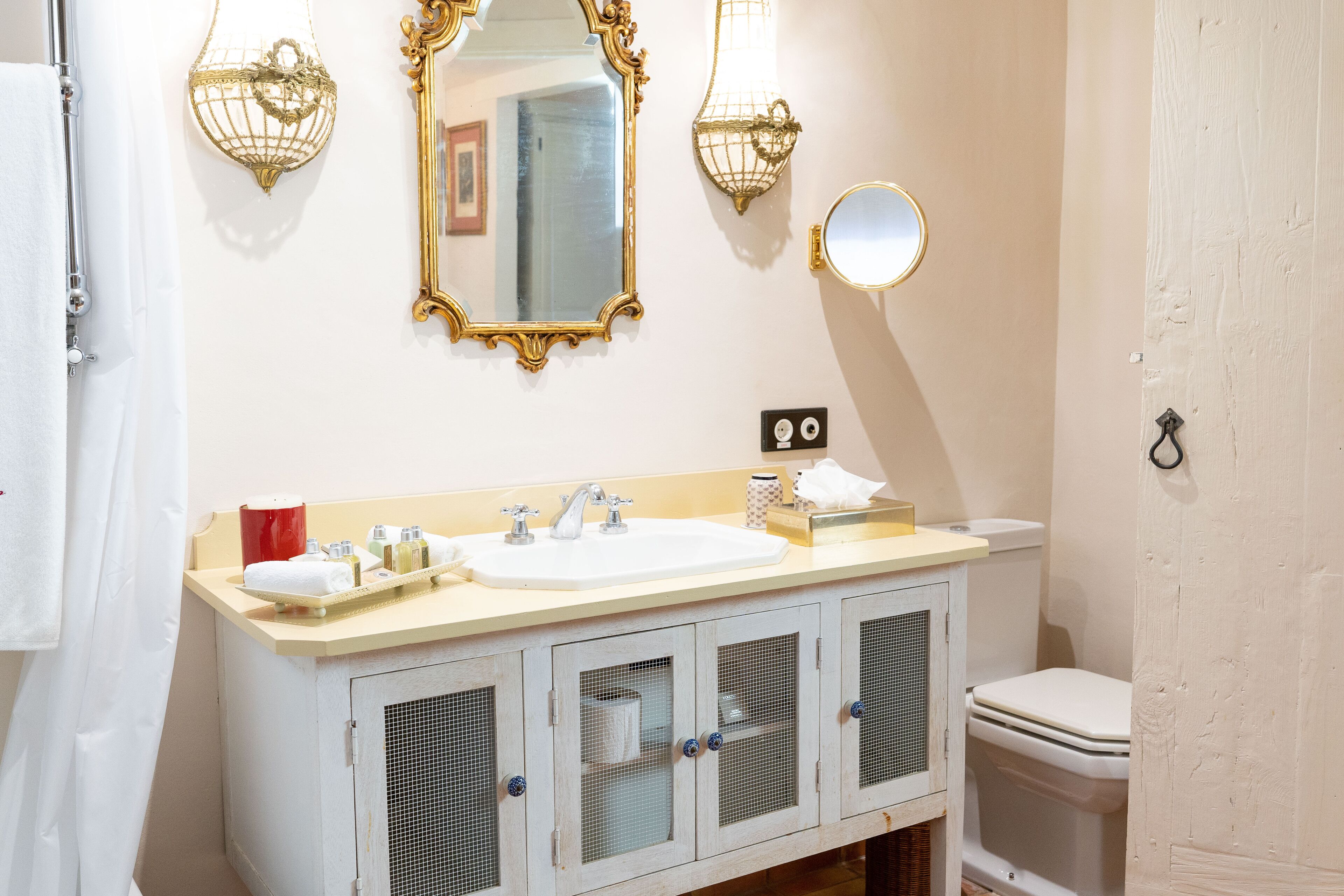 Un baño con un lavamanos blanco, dos espejos, un inodoro y una cortina de ducha.