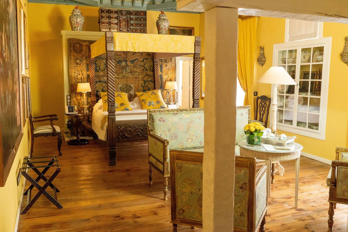 A traditional bedroom with a four-poster bed, wooden flooring, and classic furniture.