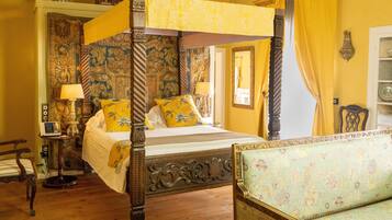 Ein Himmelbett mit Baldachin, ein Sofa mit Blumenmuster und ein Holzboden.
