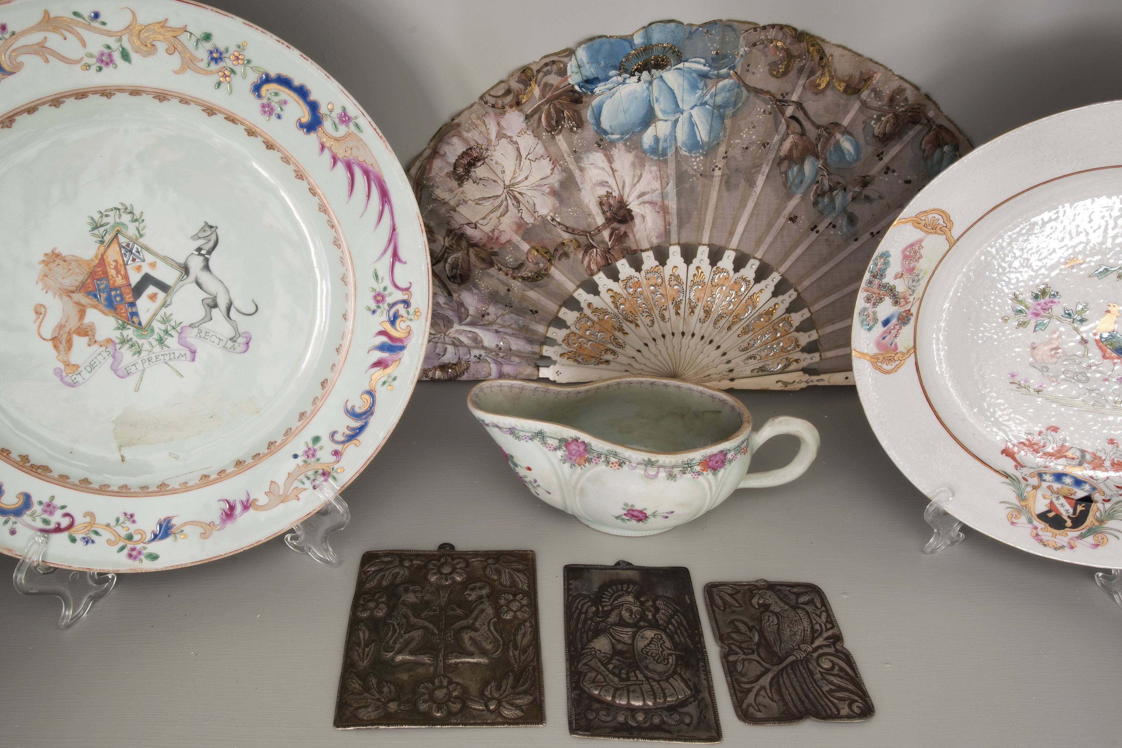 Une collection d’assiettes anciennes, un éventail et trois petites plaques de métal.