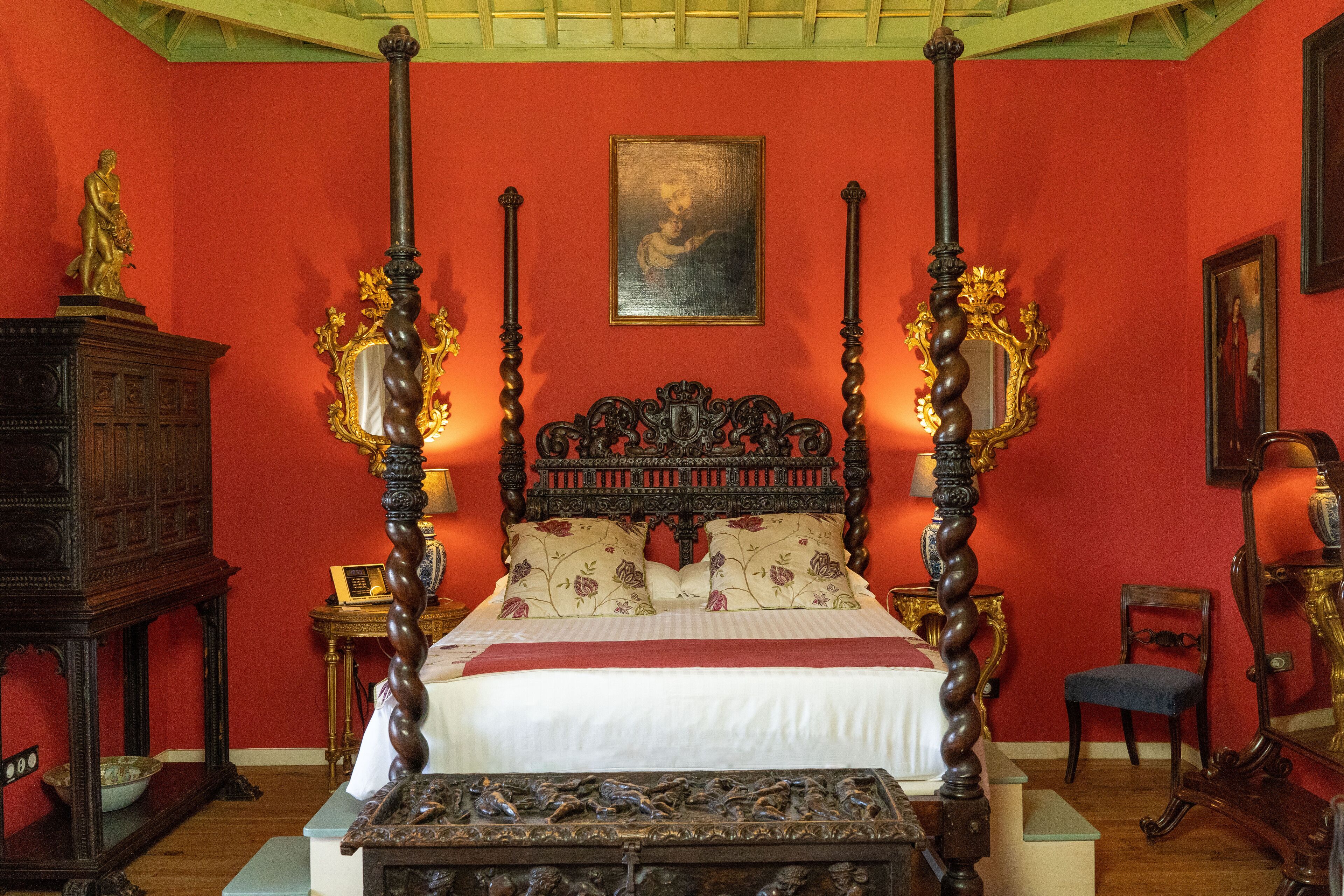 Een slaapkamer met een hemelbed, een houten kast en een stoel.