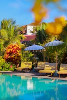 Una piscina al aire libre, sombrillas, sillones reclinables de piscina