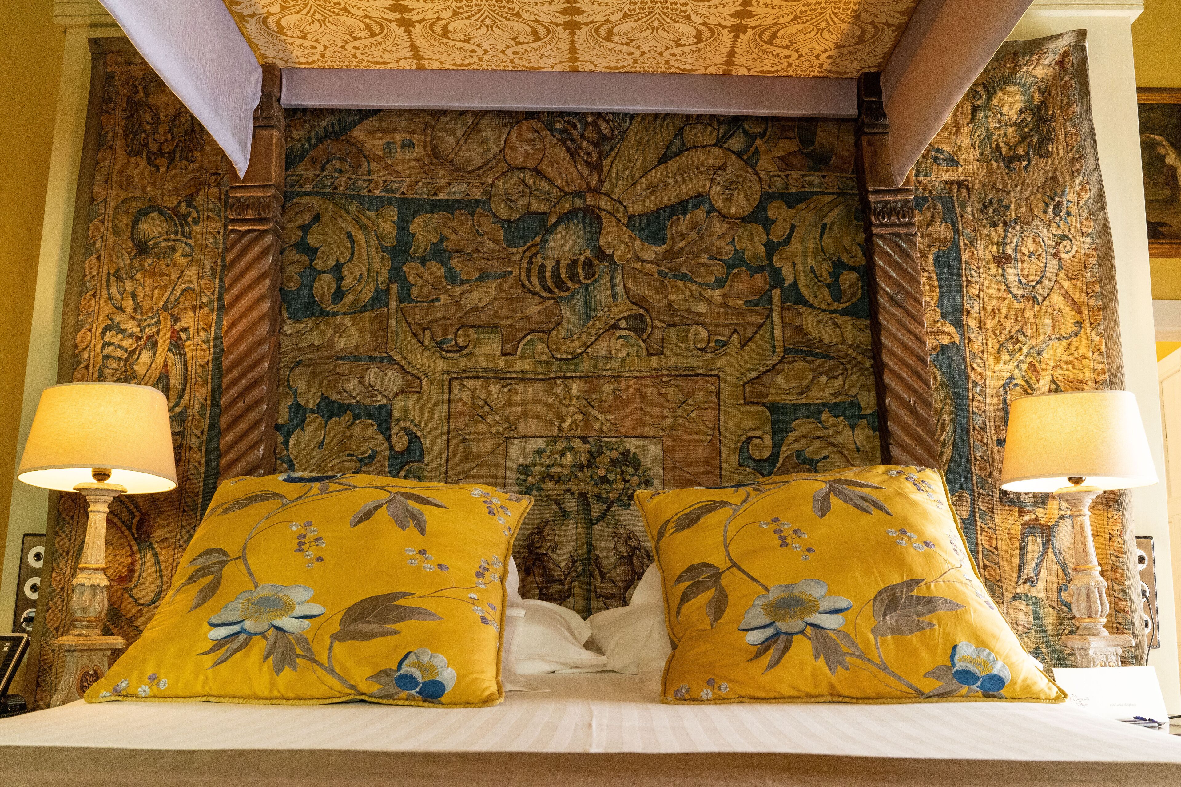 A bed with floral pillows, a decorative headboard, and two bedside lamps.