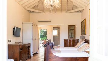 Une chambre à coucher avec un lit en bois, un lustre, une télévision et une armoire.