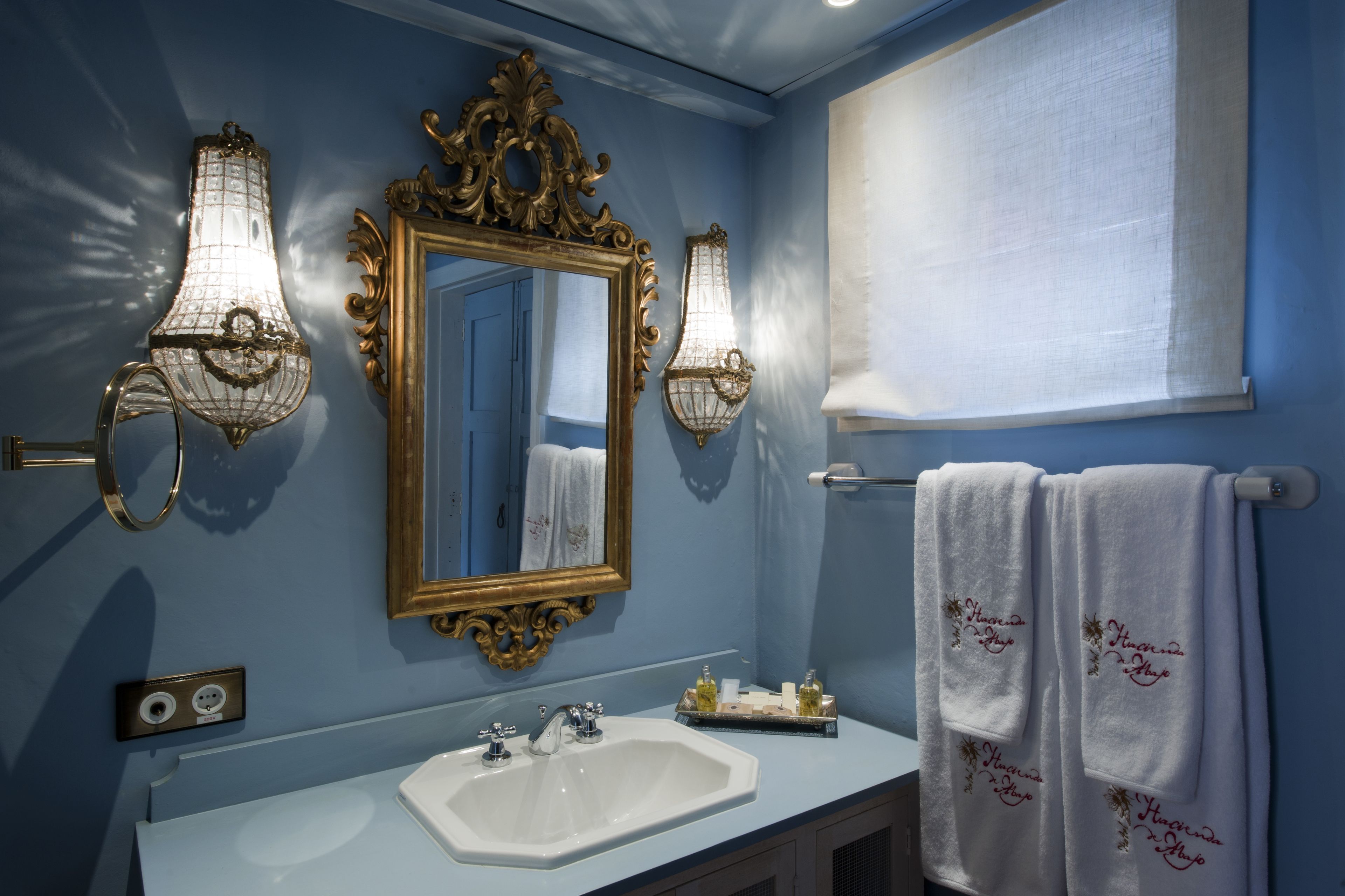 A bathroom with a sink, mirror, and two wall-mounted lights.