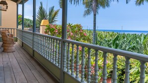 A wooden balcony with a railing, overlooking a lush garden and the ocean. - Hotel Hacienda de Abajo - Adults Only (Tazacorte)