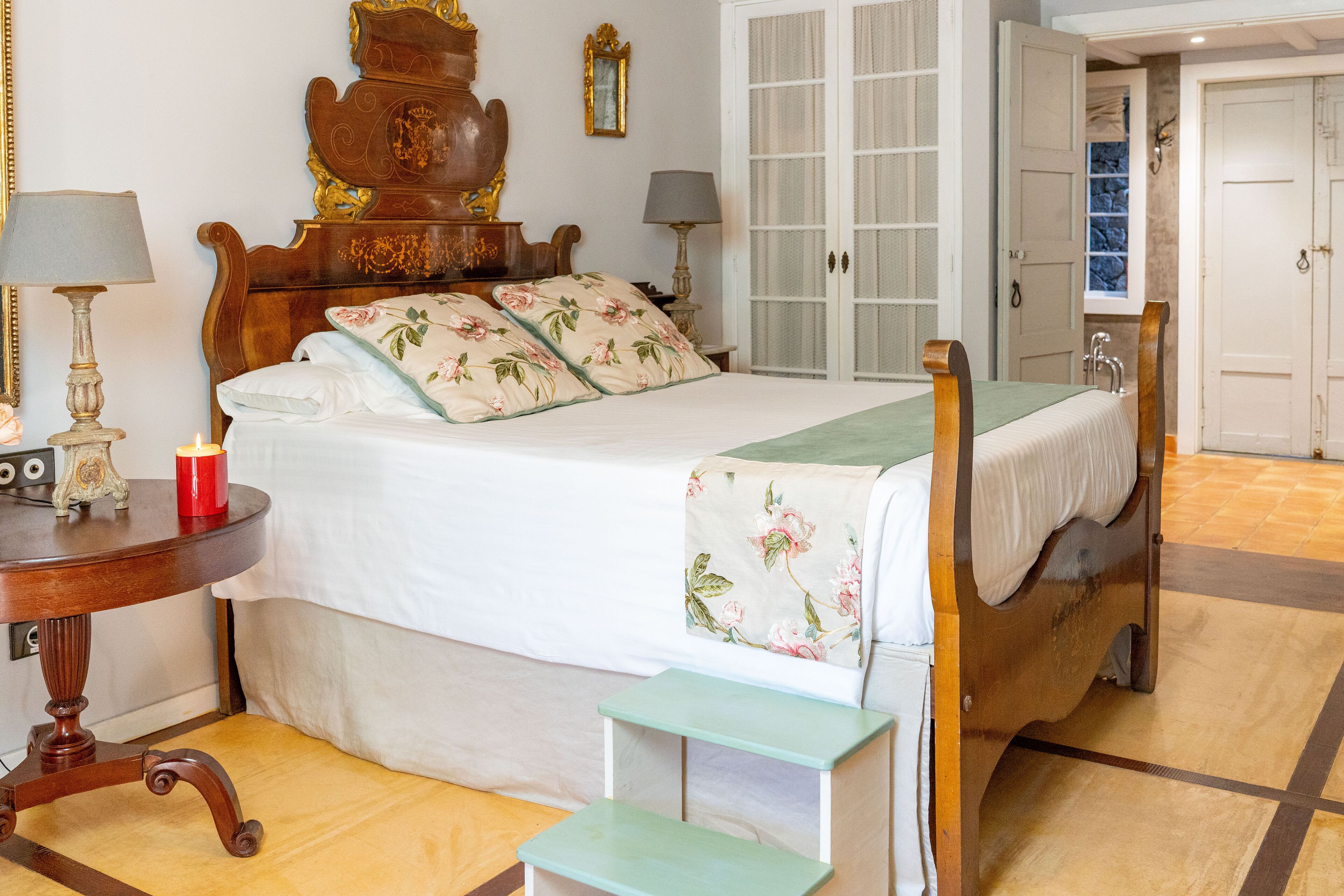 Un dormitorio con cama de madera, mesitas de noche y una silla verde.