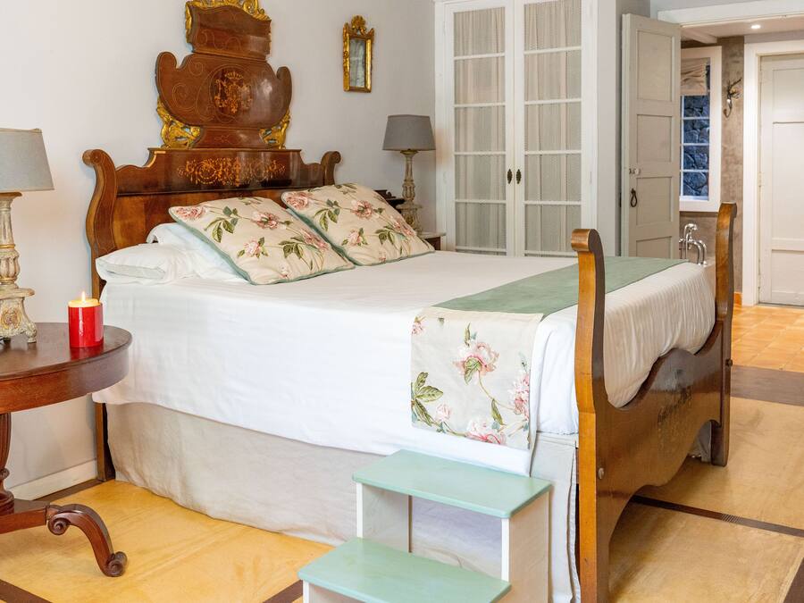A bedroom with a wooden bed, bedside tables, a nightstand, and a green chair.