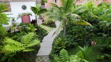 Un jardín exuberante con un sendero que lleva a un edificio blanco con una puerta roja.