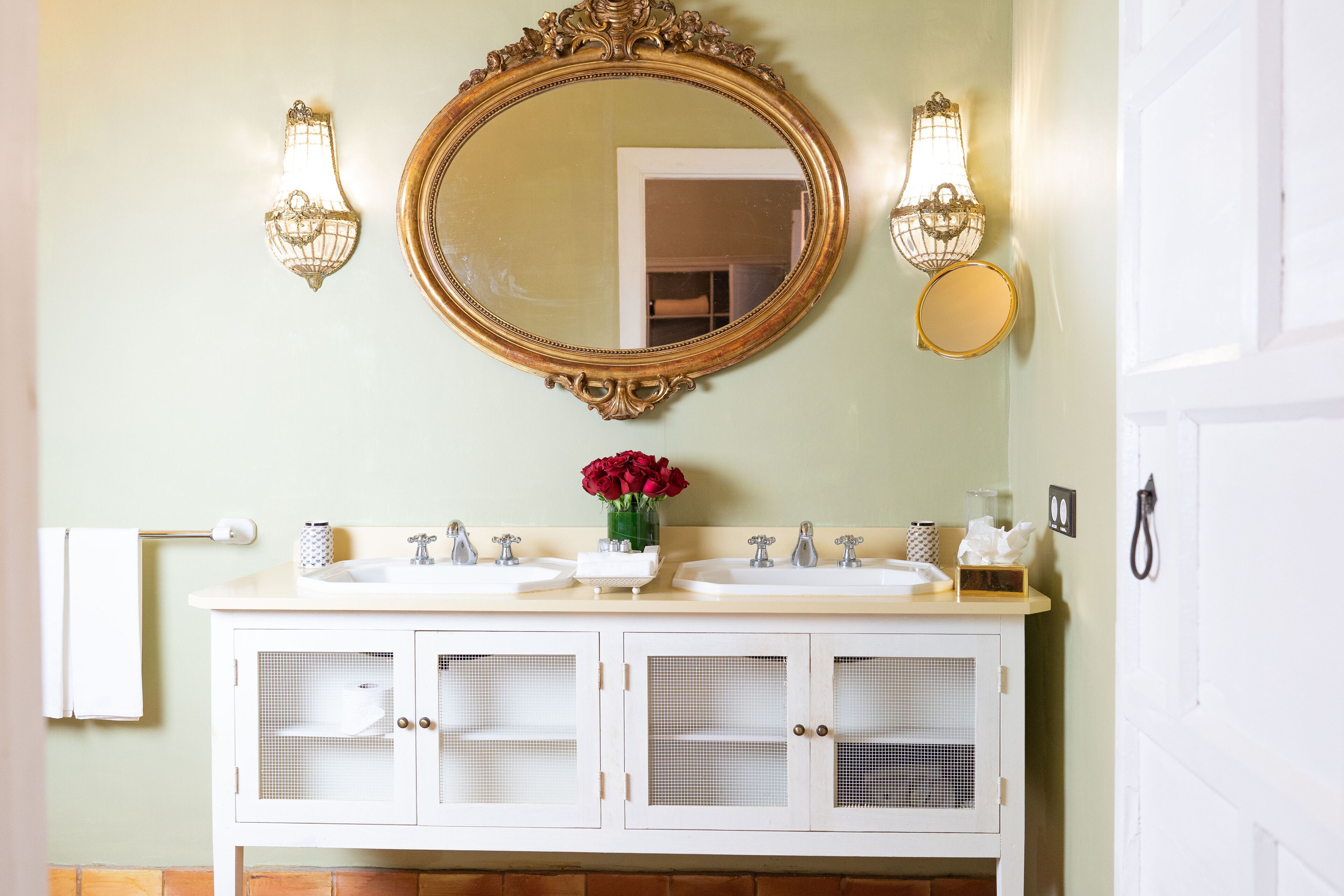 A bathroom with two sinks, a large mirror, and wall sconces.