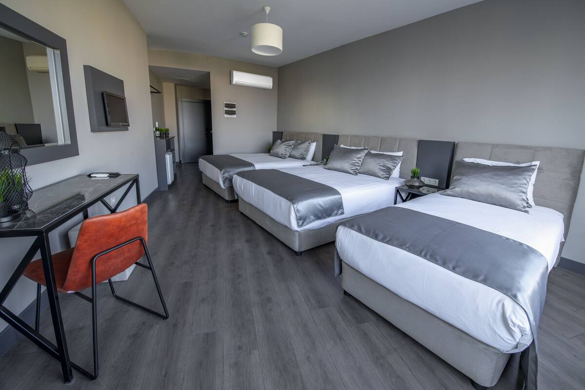 A modern hotel room with two beds, a desk, and a chair.