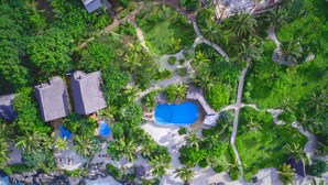 An aerial view of a tropical resort with a large swimming pool, palm trees, and a beach area. - The Zanzibari (Nungwi)