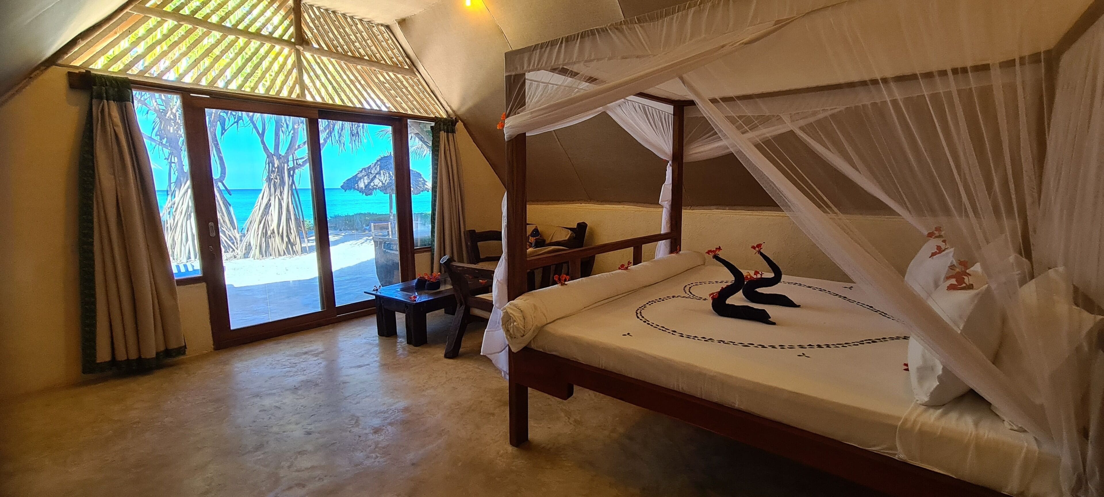 A bedroom with a bed, a desk, and a view of the beach.