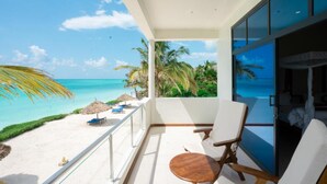 A balcony with a view of the ocean and palm trees, a white chair, and a small table. - The Zanzibari (Nungwi)