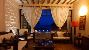 A cozy room with a stone floor, wooden furniture, and a view of the sea at night. - The Zanzibari (Nungwi)