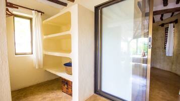 A room with a sliding glass door, a window with a curtain, a shelf with a basket, and a wooden cabinet.