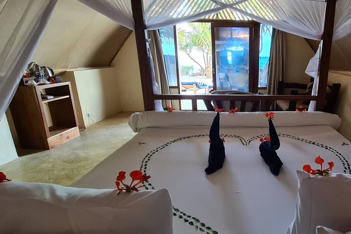 A tent-style room with a bed, a wooden nightstand, and a view of the outside.