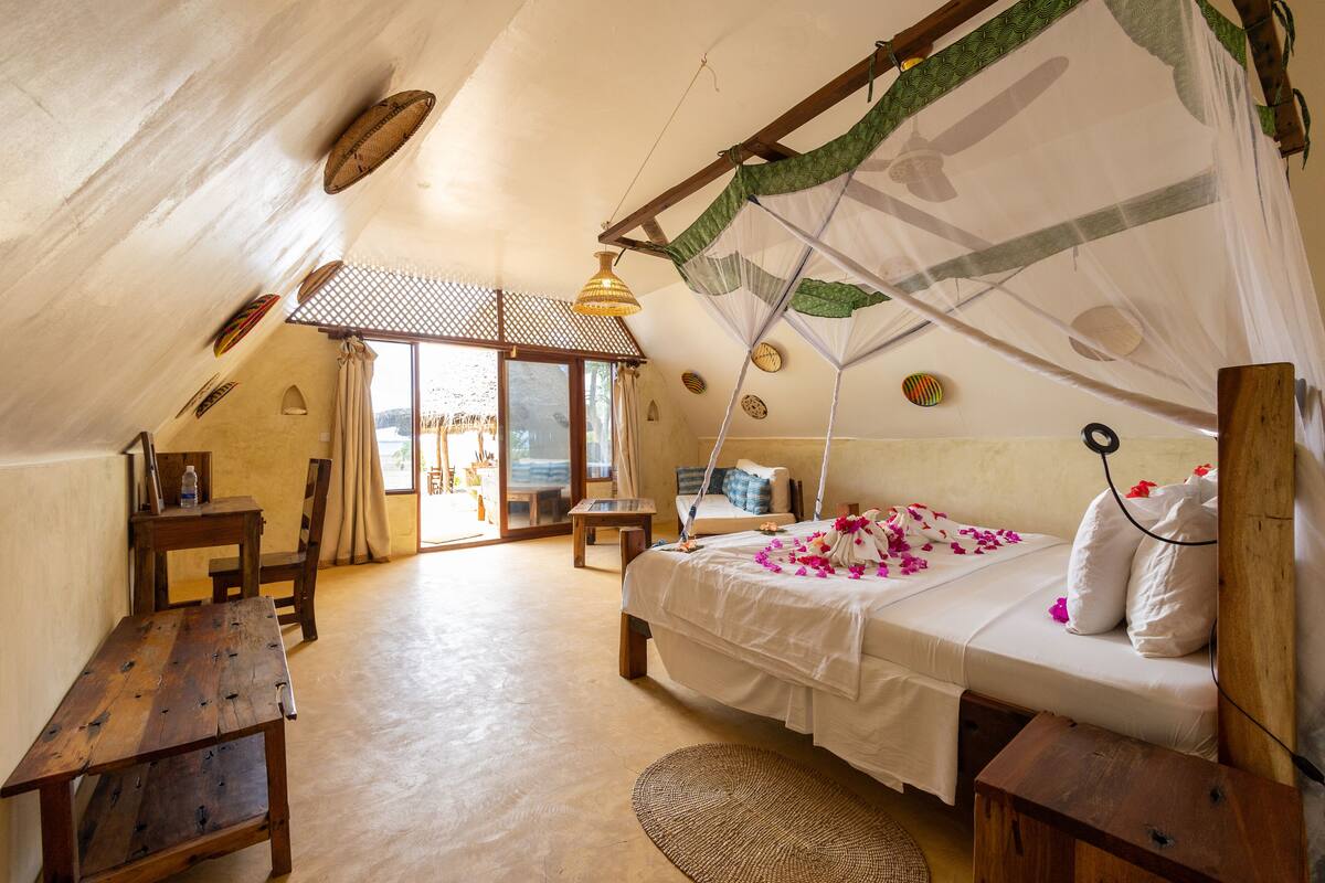 A cozy bedroom with a bed, wooden furniture, and a view through a window.