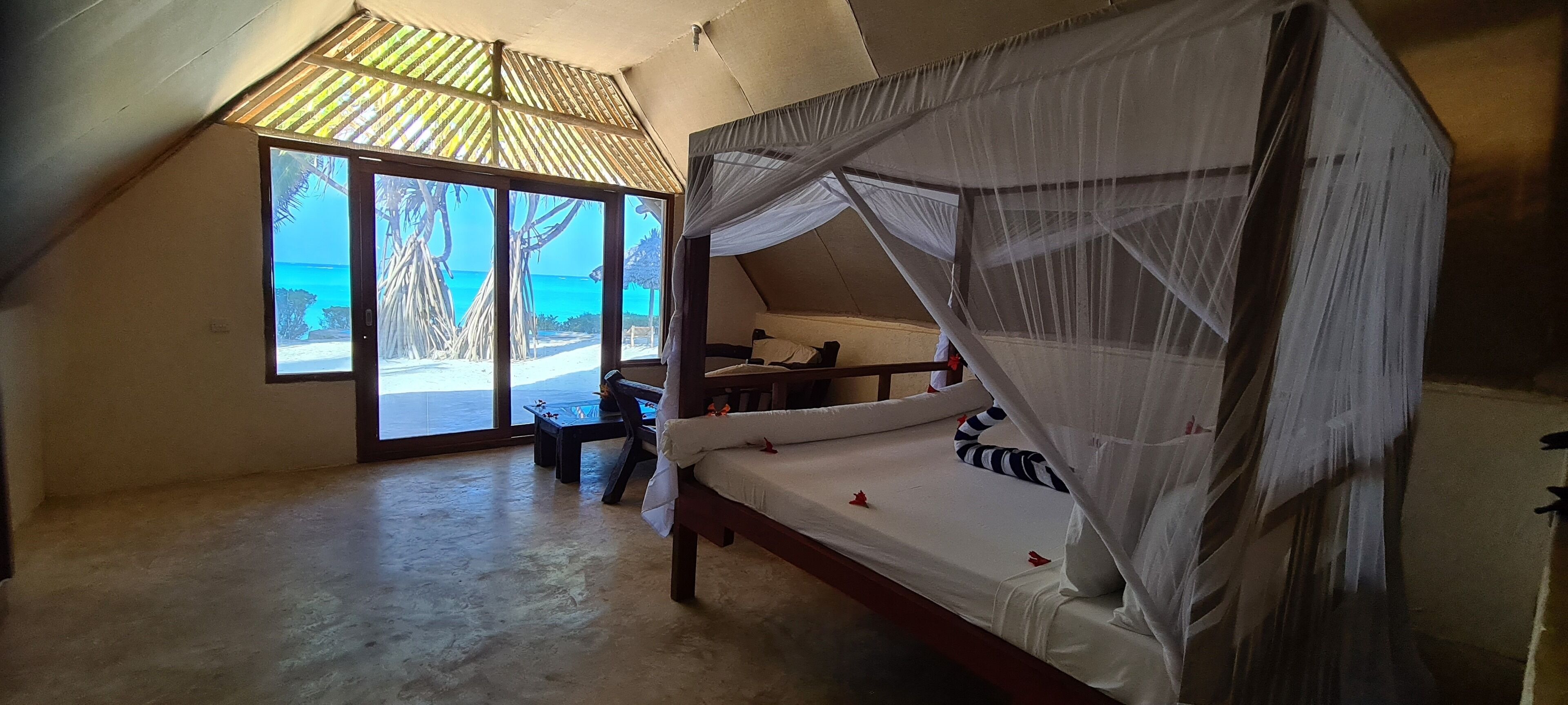 Un dormitorio con cama, una mesita y vistas a la playa.