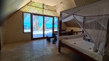 Un dormitorio con cama, una mesita y vistas a la playa.