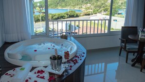 Una habitación con un ventanal grande, bañera de hidromasaje, una mesa de comedor y una silla.