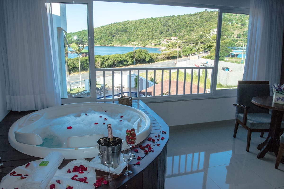 A room with a large window, a hot tub, a dining table, and a chair.