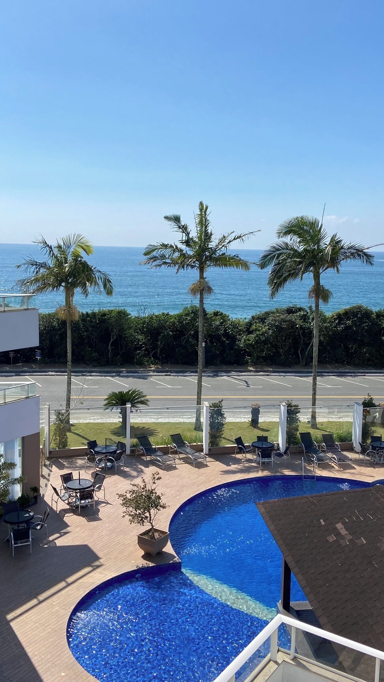 A pool area with lounge chairs and a view of the ocean.