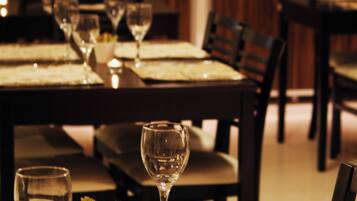 A dining table set with wine glasses, plates, and a candle.